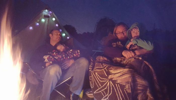 Family wrapped up warm in front of the campfire
